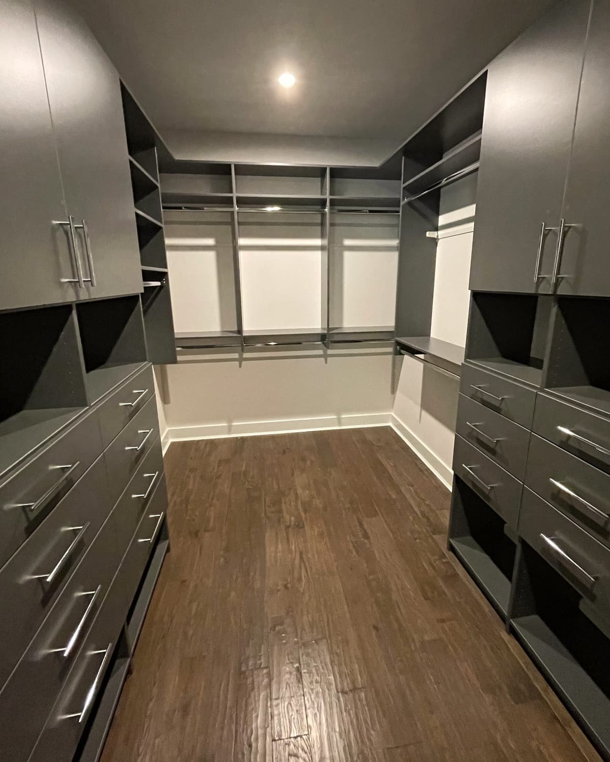 Modern dark gray walk-in closet with wood floors
