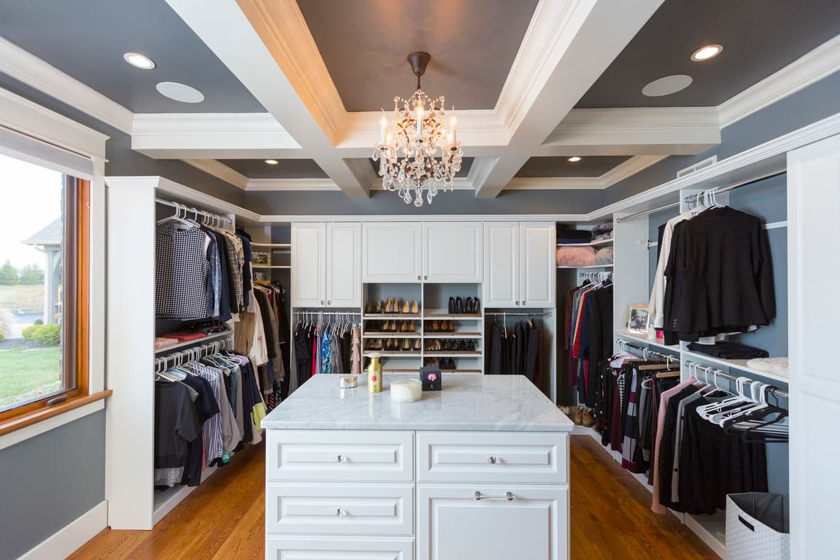 Luxury walk-in closet with chandelier and coffered ceiling