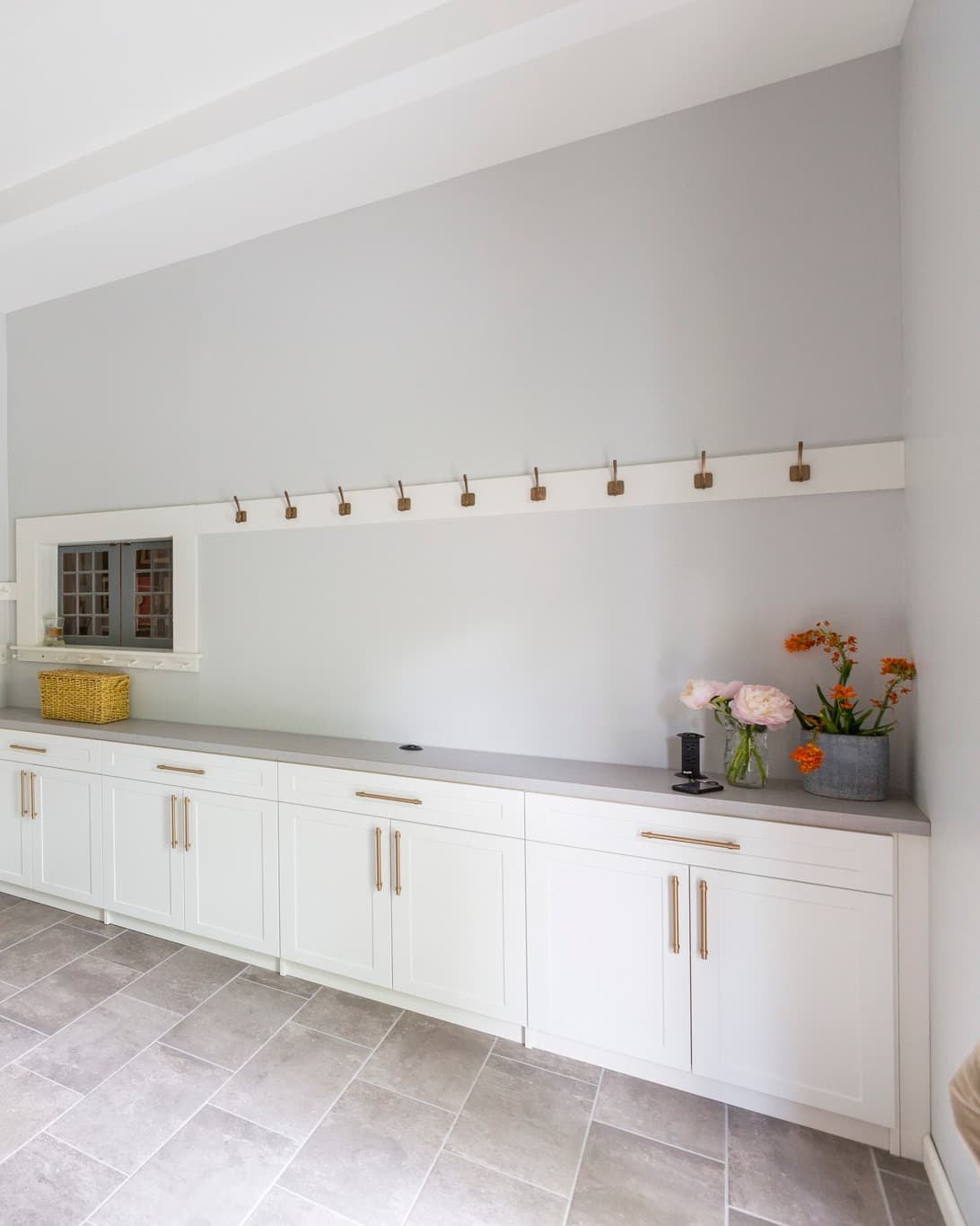 Mudroom cabinets with brass coat hooks and countertop